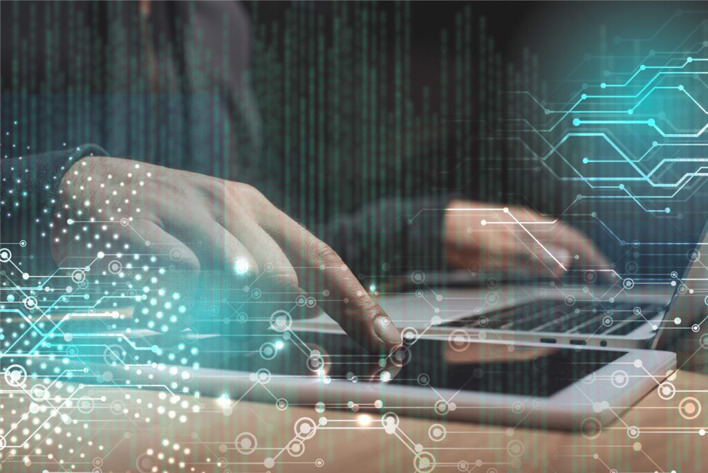 a hand typing on a phone and laptop