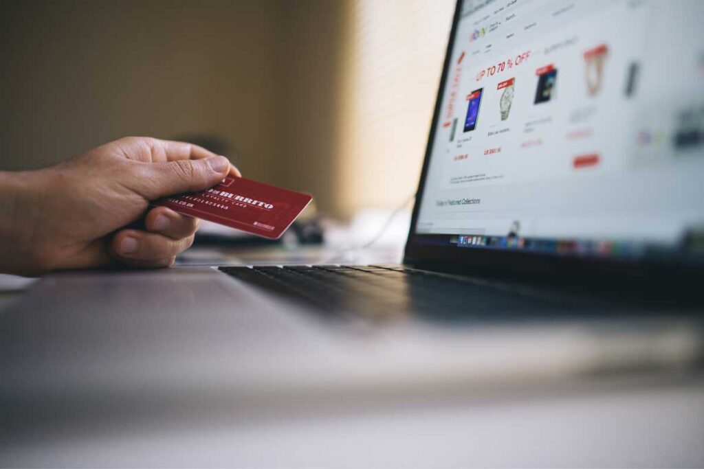 a hand holding a credit card in front of a laptop screen